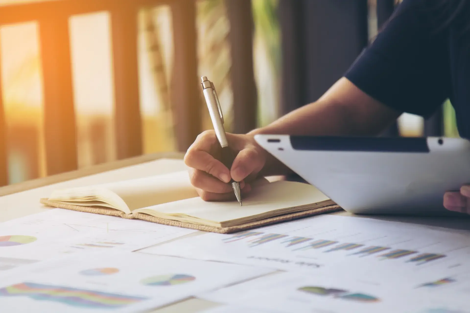 Pessoa estudando com tablet e caderno usando o método de imersão de inglês online