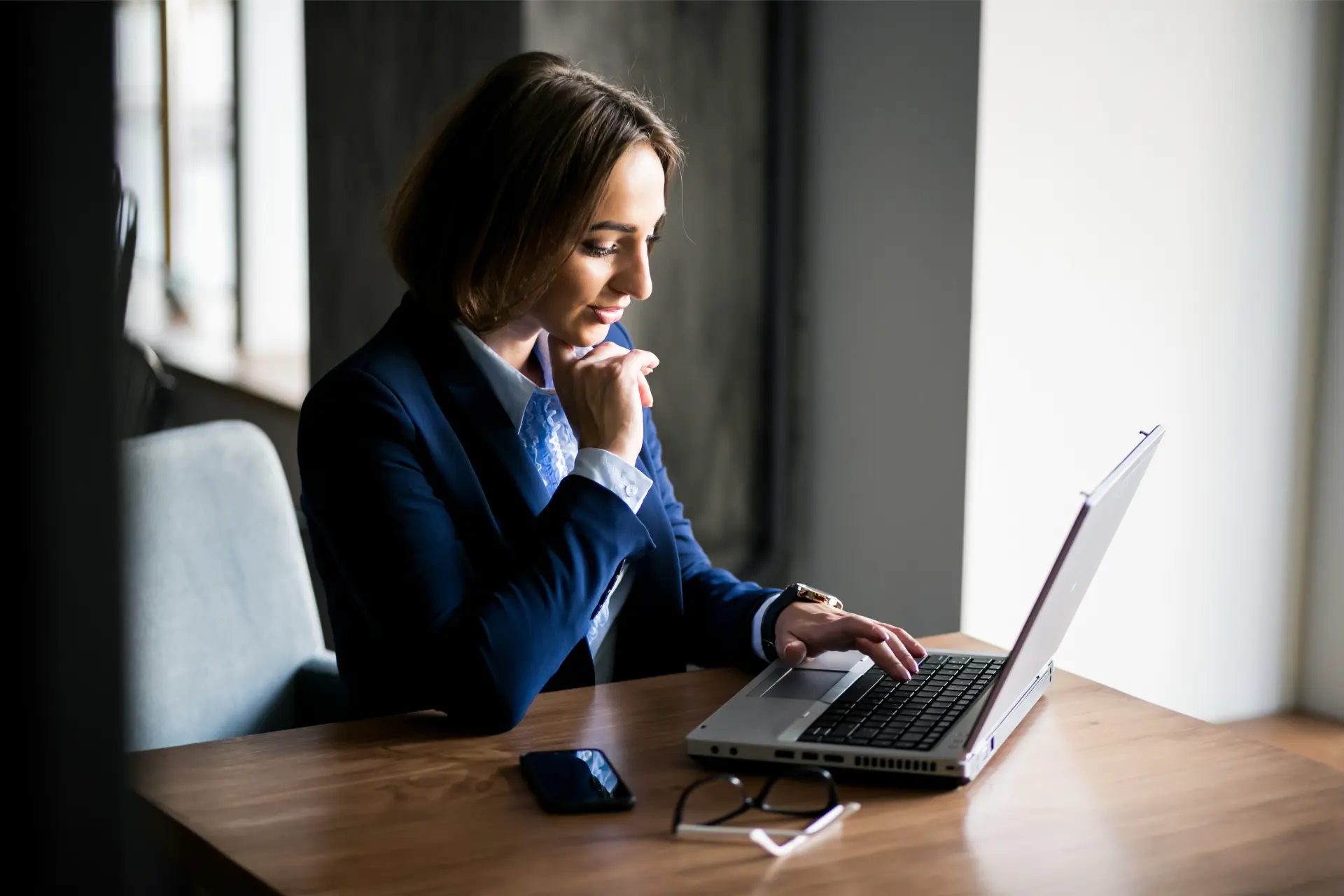 Executiva concentrada estudando preparação para certificações TOEFL TOEIC em laptop em escritório moderno