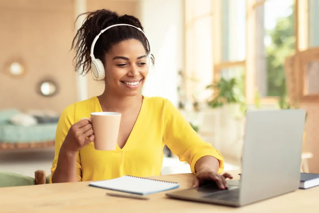 Profissional com fones estudando inglês no laptop com uma xícara de café