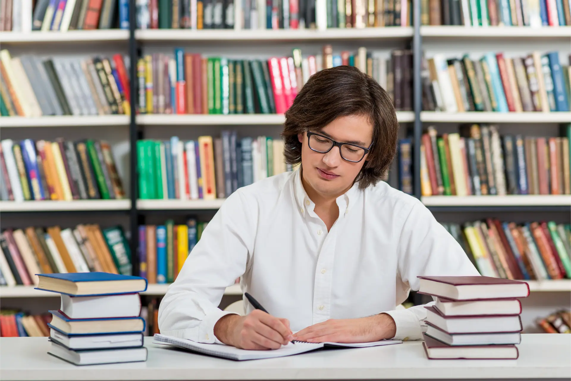 Estudante lendo papers e praticando inglês acadêmico cercado de livros na biblioteca